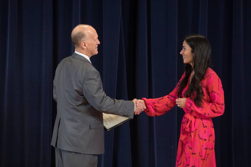 Dean Potteiger shaking hands with a graduate student and presenting them their award